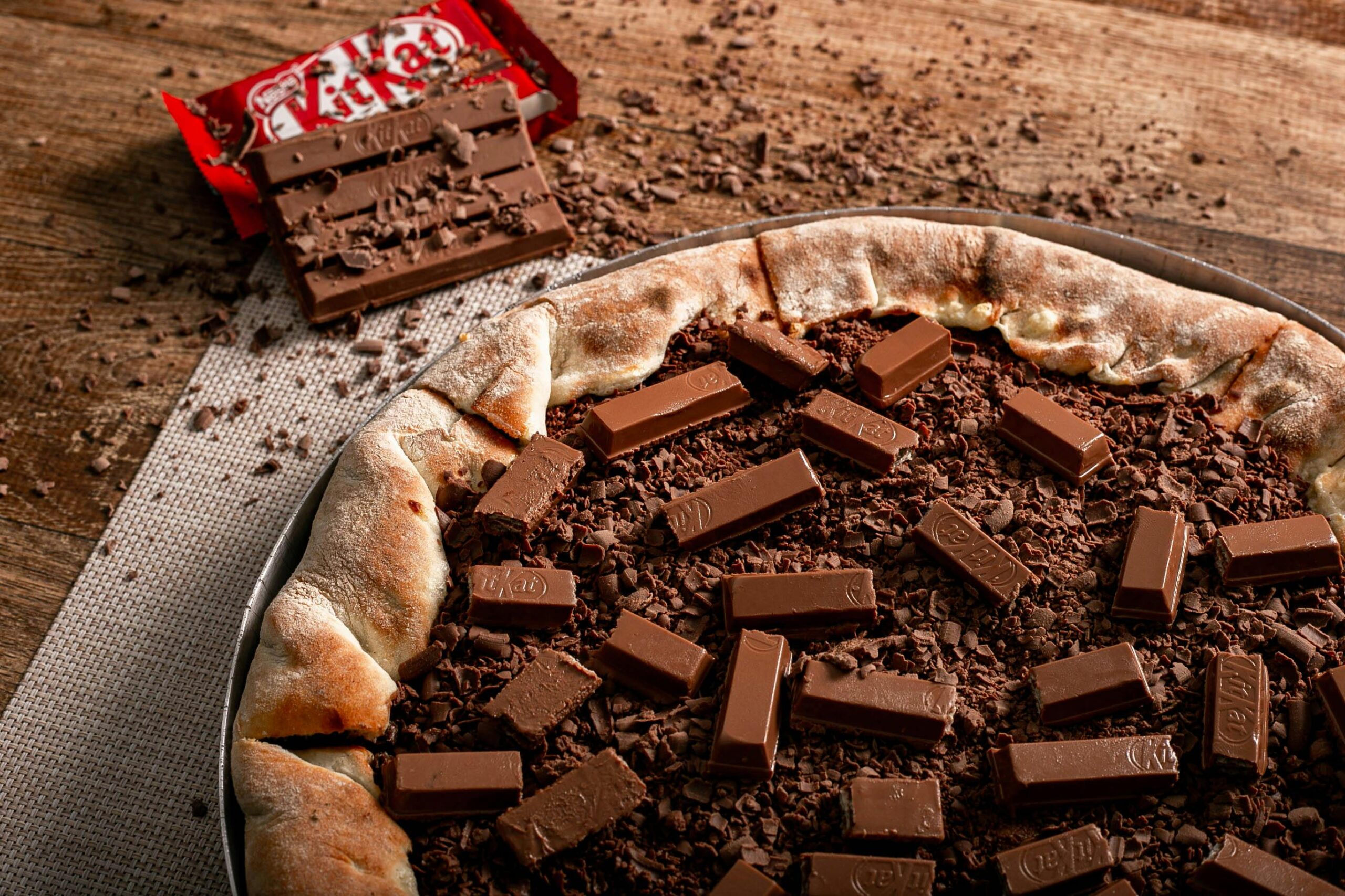 Mouth-watering chocolate pizza topped with KitKat bars, perfect for dessert lovers.